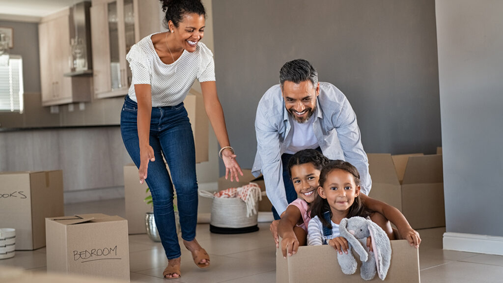 Smiling family moving boxes into their new home